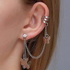 Silver butterfly earring with chain detail worn on an ear against a neutral background